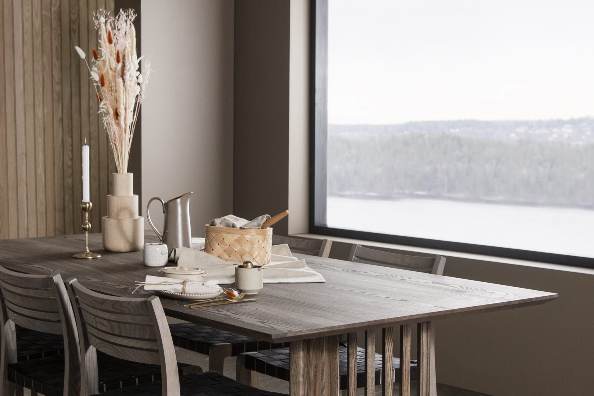 Custom wooden dining table in a grey wash with a forest view through the window